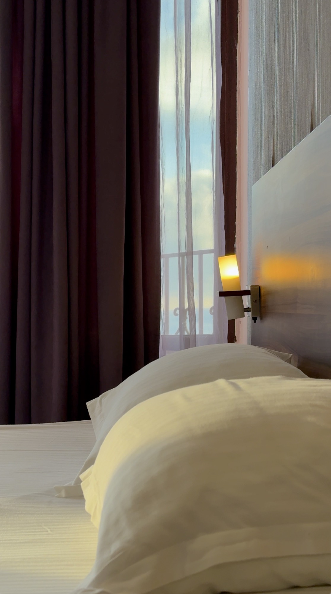 Cama do Hotel Ellinis com vista da varanda ao entardecer
