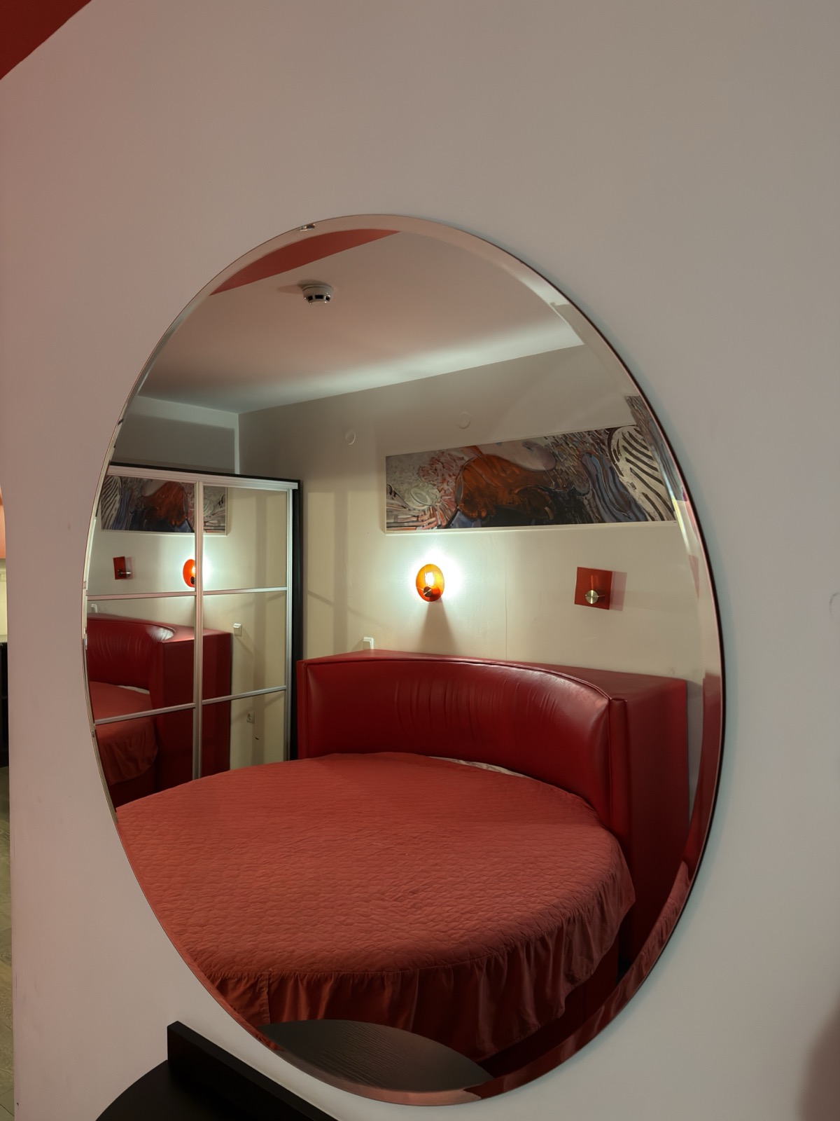 Quarto com cama redonda refletida no espelho