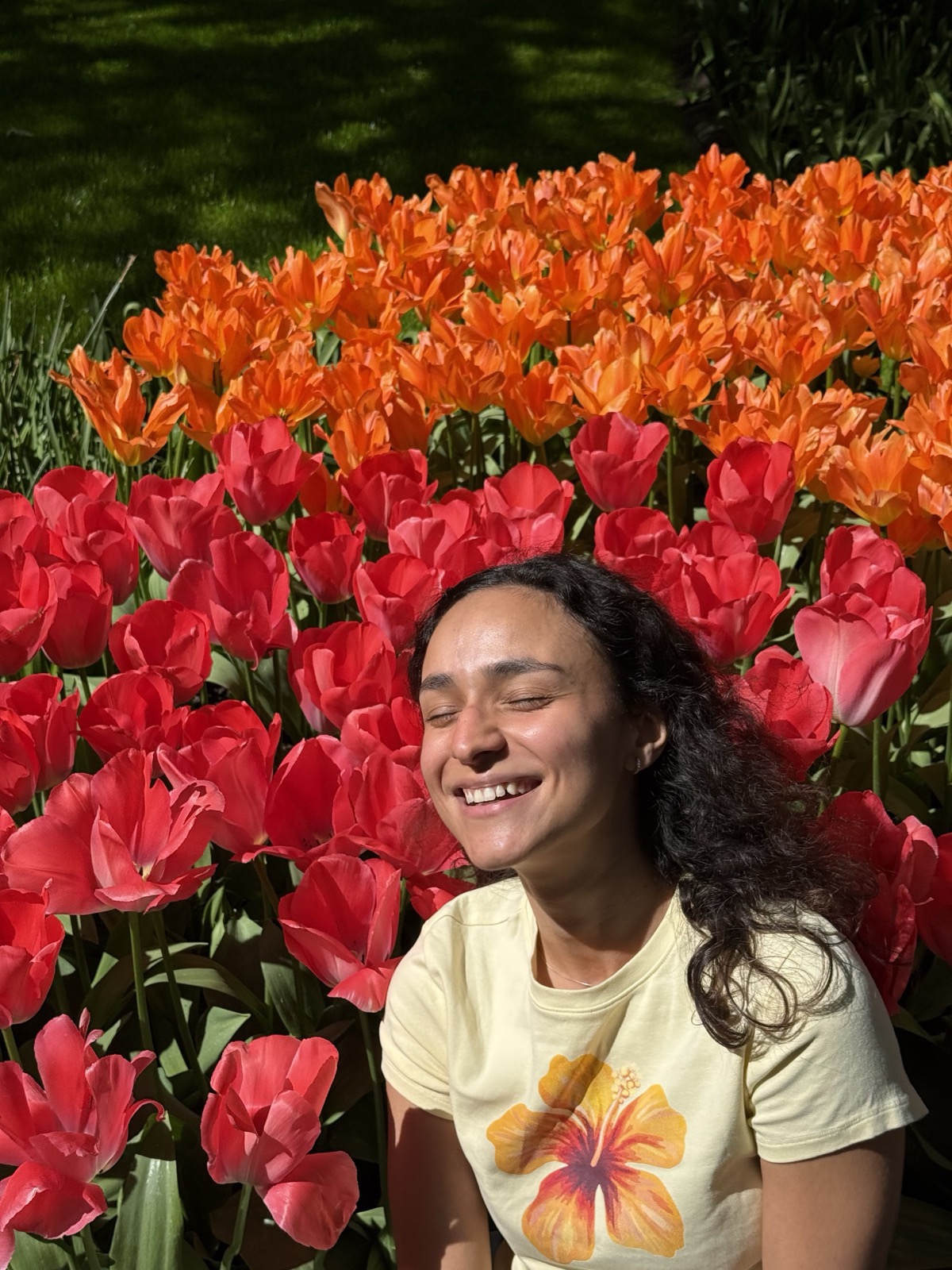 Fran sorrindo num campo de tulipas vermelhas e laranjas